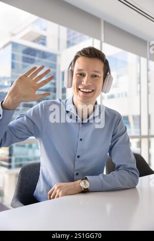 Happy confident young businessman waving hello, looking at camera Stock Photo