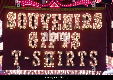 A neon sign for Souvenirs Gifts T-Shirts. The sign is lit up and has a red background Stock Photo