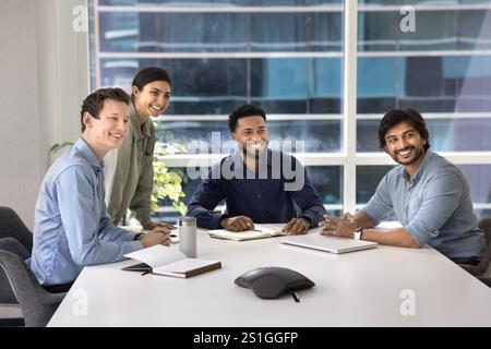 Happy multiethnic business colleagues sitting at large table Stock Photo