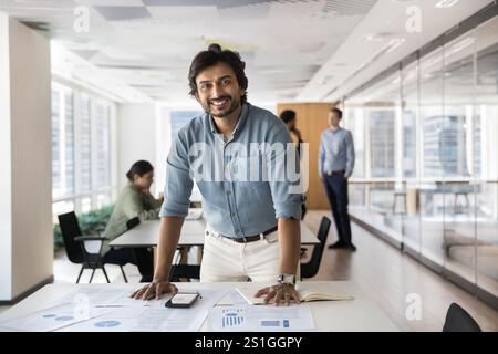 Happy Indian businessman, company owner, executive posing in open office Stock Photo
