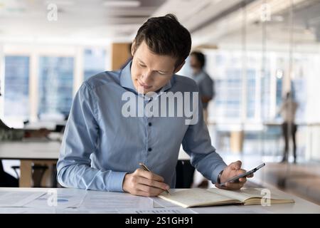 Focused young Caucasian company manager man analyzing project documents Stock Photo