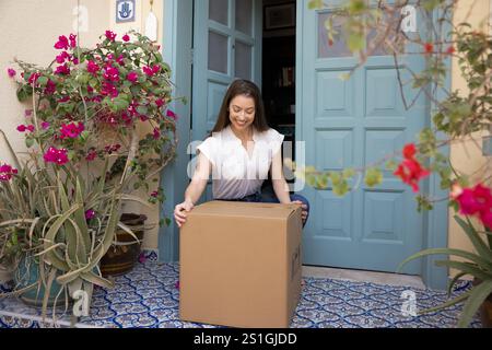 Happy young customer woman taking awaited parcel from doorstep Stock Photo