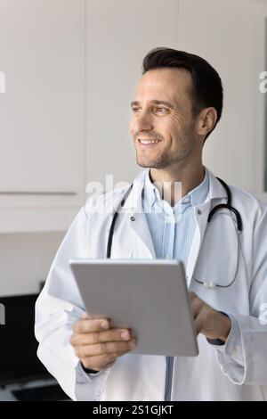 Happy general practitioner doctor using medical application on tablet Stock Photo