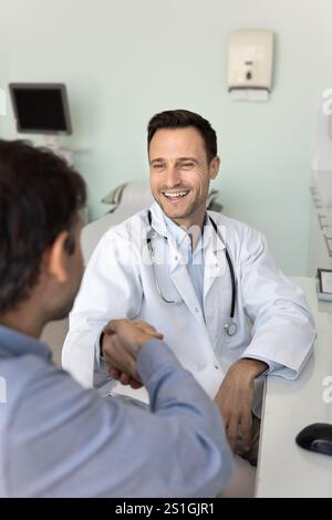 Positive satisfied male doctor giving handshake to healthy patient Stock Photo