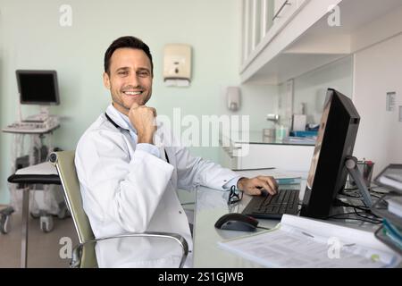 Happy doctor man working at computer in ultrasound scanning room Stock Photo