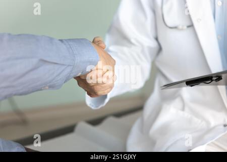 Cropped shot of male doctor and patient shaking hands Stock Photo