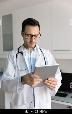 Serious young doctor man using digital tablet for work Stock Photo
