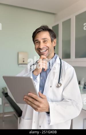 Cheerful Hispanic male general practitioner man using tablet Stock Photo