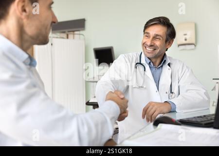 Positive successful Latin doctor giving handshake to patient Stock Photo