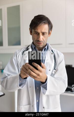 Serious doctor man using mobile phone for Internet communication Stock Photo