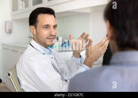 Positive male doctor talking to man at workplace Stock Photo