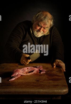 A man chopping up rabbit meat Stock Photo