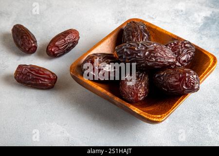 Large dates fruit in a wooden bowl on bright background Stock Photo