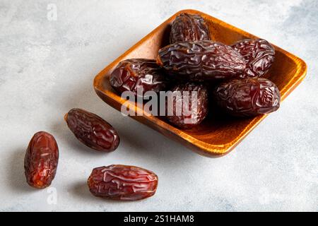 Large dates fruit in a wooden bowl on bright background Stock Photo