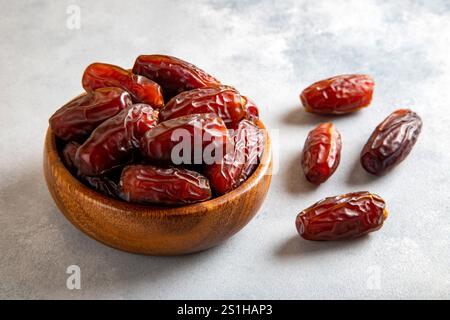 Large dates fruit in a wooden bowl on bright background Stock Photo