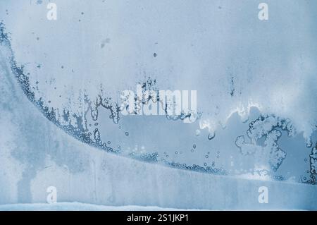 A window with frost on it. The frost is in the shape of a wave. The window is on the side of a building Stock Photo