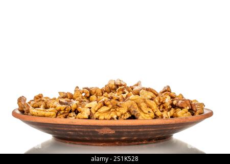 Shelled walnuts on a clay plate, close-up, isolated on a white background. Stock Photo