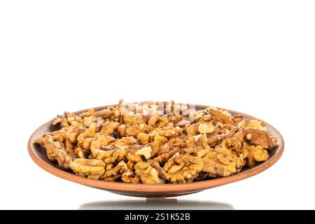 Shelled walnuts on a clay plate, close-up, isolated on a white background. Stock Photo