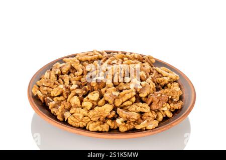 Shelled walnuts on a clay plate, close-up, isolated on a white background. Stock Photo