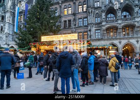 Munich, Germany - December 4, 2024: Crowds gather in front of a gluhwein mulled wine stand at Marienplatz, in front of the New Town Hall Rathaus Stock Photo