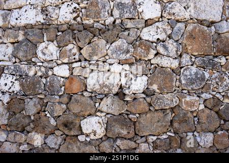 Colorful fence made of various colors and sizes of stones in a sunlight. Torrefano, Sicily, Italy. Stock Photo