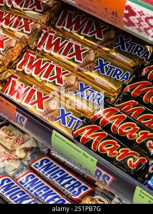Bobruisk, Belarus - December 29, 2024: A vibrant selection of popular chocolate bars fills the shelves of a busy convenience store. Twix, Mars, and Sn Stock Photo
