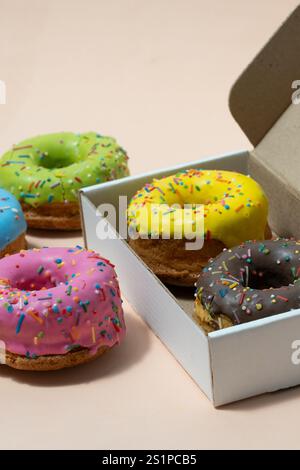 Colorful donuts in gift box on beige background Stock Photo