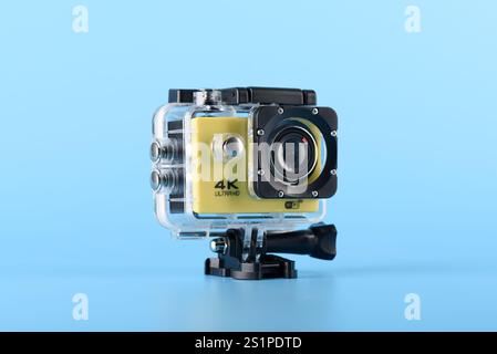 Moscow, Russia - January 3, 2025: Yellow 4K action camera in a waterproof case on a blue background, showcasing modern compact technology for filming Stock Photo