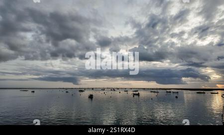 looking out to the water from faro, portugal, on a cloudy day after sunset, with the sun peaking through the clouds. Stock Photo