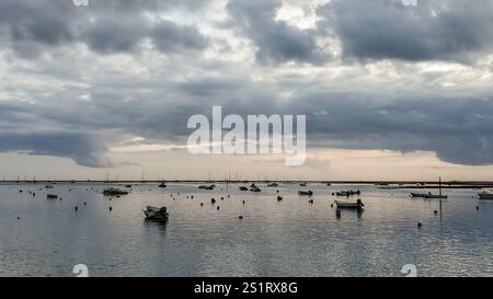 looking out to the water from faro, portugal, on a cloudy day after sunset, with the sun peaking through the clouds. Stock Photo