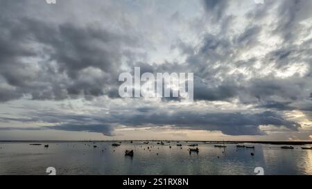 looking out to the water from faro, portugal, on a cloudy day after sunset, with the sun peaking through the clouds. Stock Photo