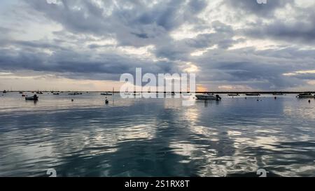 looking out to the water from faro, portugal, on a cloudy day after sunset, with the sun peaking through the clouds. Stock Photo