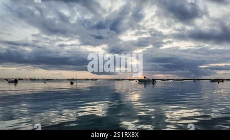 looking out to the water from faro, portugal, on a cloudy day after sunset, with the sun peaking through the clouds. Stock Photo
