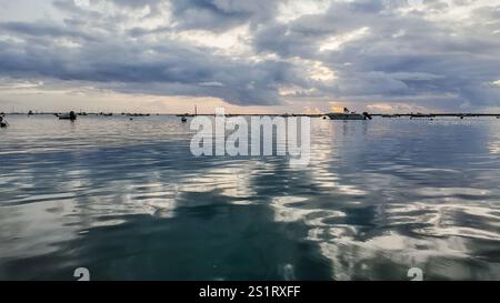 looking out to the water from faro, portugal, on a cloudy day after sunset, with the sun peaking through the clouds. Stock Photo