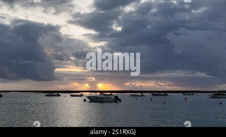 looking out to the water from faro, portugal, on a cloudy day after sunset, with the sun peaking through the clouds. Stock Photo