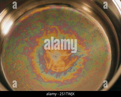 Iridescent color spots on the bottom of a stainless steel pan. Light interference in thin films. Concept of optical effects on familiar objects. Visua Stock Photo
