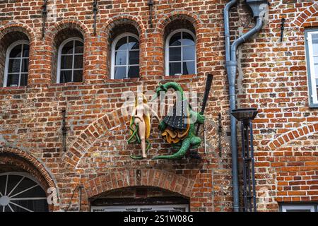 Sculpture of a woman with a green dragon at the wall of house in Luebeck. Sculpture of a woman with a green dragon at the wall of house Stock Photo