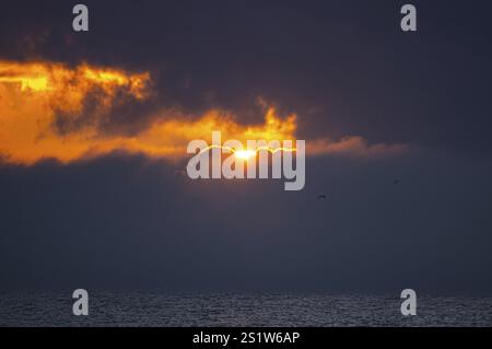 Sunrise over the sea on the Baltic Sea. The sun shines through dark clouds. Sunrise at the seaside, shining through dark clouds Stock Photo