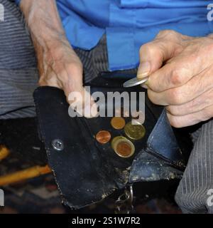 Old-age poverty: An old man's hands hold an open, worn wallet with a few euro coins. Square format. Old-age poverty: Old man's hands hold an open, wor Stock Photo