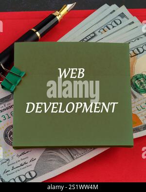 Concept word WEB DEVELOPMENT written on a sticker on the background of dollar bills. Stock Photo