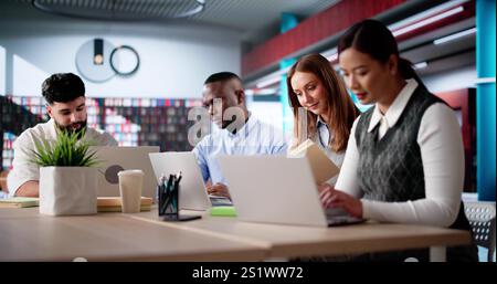 Students Learning Online At University Library Using Laptops Stock Photo