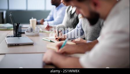 Studying In Classroom At Campus. Students Writing In Class Stock Photo