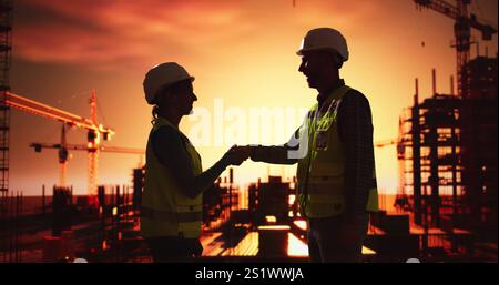Silhouette Of Two Architects At Construction Site Shaking Hands Stock Photo