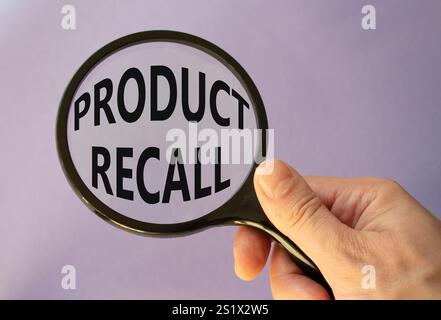 Product recall symbol. Concept words Product recall on magnifying glass. Beautiful purple background. Businessman hand. Business and Product recall co Stock Photo
