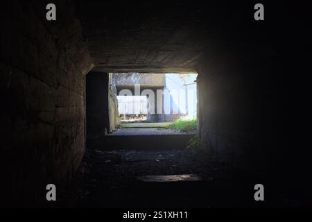 Dirt low passage in the shade under a concrete bridge with a lake at the end of the structure Stock Photo