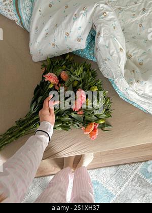 This photo captures a calm spring moment in Istanbul, with a vibrant bouquet of peach-toned blooms resting on a soft bed adorned with floral-patterned Stock Photo