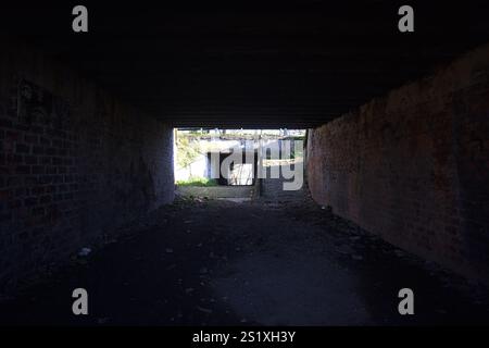 Dirt low passage in the shade under a concrete bridge with a lake at the end of the structure Stock Photo