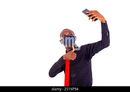portrait of a young businessman wearing a fabric medical mask and taking a photo on a mobile phone with his thumb. Stock Photo