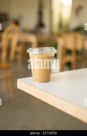 A refreshing iced coffee sits on a table in a cozy café; the perfect drink to enjoy while relaxing in a warm and inviting atmosphere, ideal for summer Stock Photo
