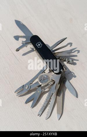 Swiss Army knife with a black handle and silver blades. The knife has a variety of tools, including a screwdriver, scissors, and a can opener Stock Photo
